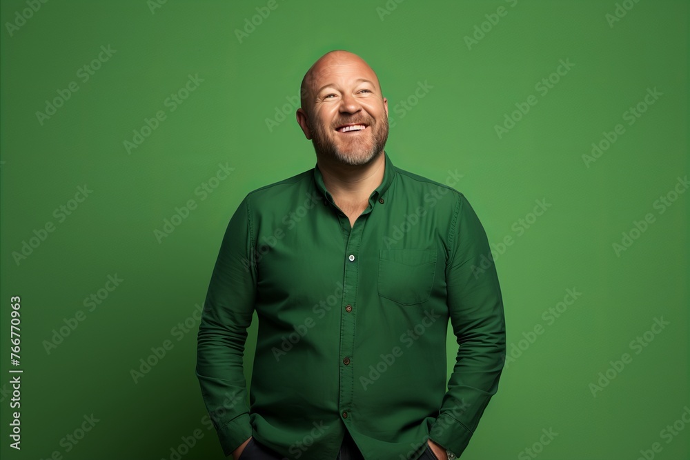 Wall mural mature bald man laughing and looking up, isolated on green background