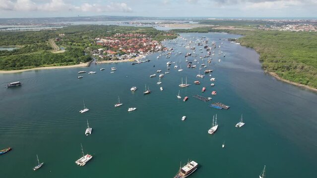 Tilt down drone shot of boats in Keramba Wayan Apel Strait on sunny day. Serangan, Denpasar, Bali.