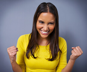 Woman, fist and celebration with smile in studio for success, goals and vision for achievement by...