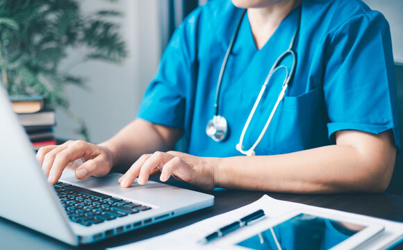 Female doctor using her laptop computer for employees management, hospital workflow and clinic staff solution on software or app. in the office.