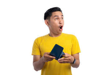 Shocked young Asian man holding empty wallet and looking aside at copy space isolated on white background