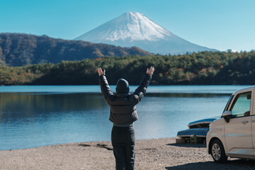 Woman tourist enjoy with Fuji Mountain at Lake Saiko, happy Traveler sightseeing Mount Fuji and road trip Fuji Five Lakes. Landmark for tourists attraction. Japan Travel, Destination and Vacation