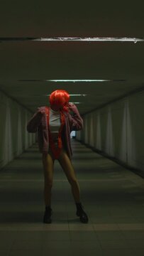 vertical shot. stylish young woman with orange hair dances in a nightclub. Music, dancing and partying with women at the concert.