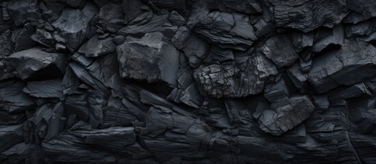 A detailed view of a solid black rock wall set against a plain black background