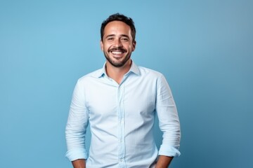 Portrait of a handsome young man smiling with hands in pockets on blue background - obrazy, fototapety, plakaty