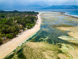 Aerial view of a huge coral reef table forming a fringing reef around a tropical island