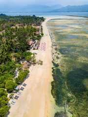 Top down aerial view of a tropical beach and resorts on a small island