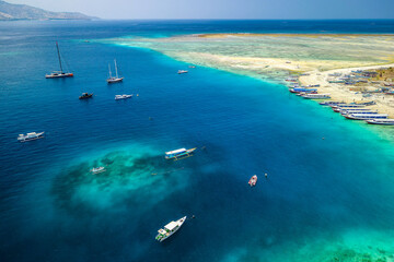 Boats on a beach and coral reef off a tiny tropical island i