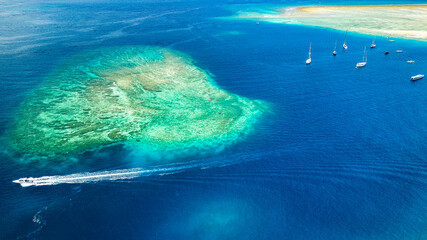 Aerial view of a fringing tropical coral reef around the coastline of a tiny island in Indonesia...