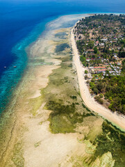 Aerial view of a reef table and coral reef off a tiny tropical island