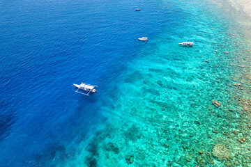 Tourist boats over the wall of a fringing coral reef in Indonesia