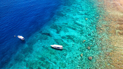 Top down aerial view of snorkel boats and tourists over a tropical coral reef in a warm ocean