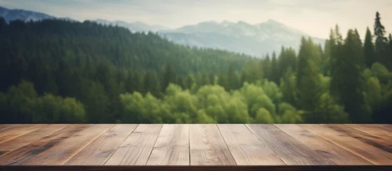 Foto op Canvas An empty wooden table surrounded by a natural landscape with a forest, grass, and trees in the background under a cloudy sky © AkuAku