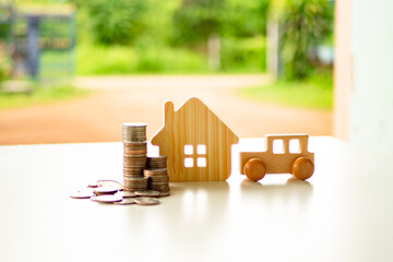 Car and house wooden model with with coins stack on table. Asset approval concepts purchases to buy...