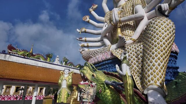 Blue skies over Wat Plai Laem Temple featuring the many-armed statue of Guanyin in Koh Samui, Thailand, vibrant religious art.
