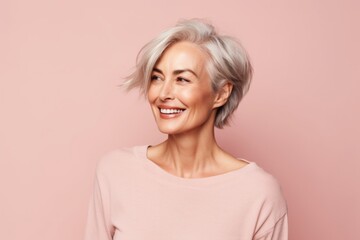 Portrait of a beautiful middle-aged woman with grey hair on a pink background
