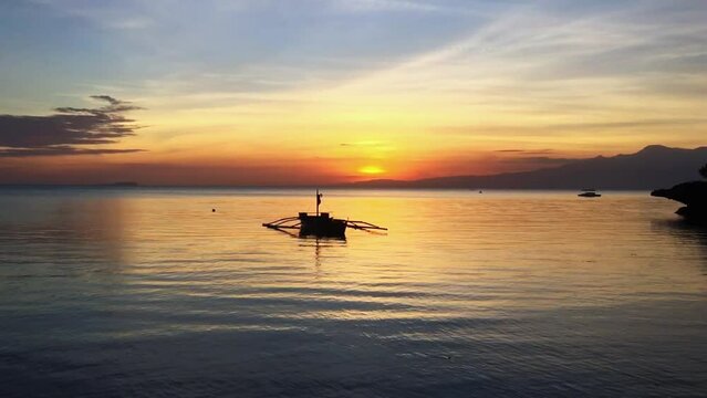 Watching the beautiful sunset with a boat silhouette in Siquijor Island. The traditional boat in the colorful water in the Philippines. The amazing landscape in the Philippines.