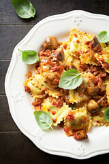 Ravioli with mushrooms and fresh basil. Dark wooden background.  Top view. Close up	