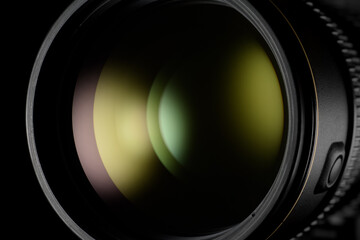 Photo or video camera lens with green reflection close-up on the black.