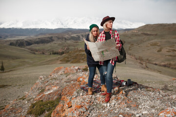Two traveler girls with map stand on rock in mountains - 766807523