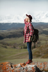 Hipster girl traveler with hat and backpack on background of mountains - 766808584