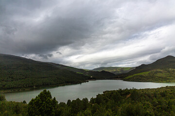 Hills and forest on the lake with dramatic sky and clouds
