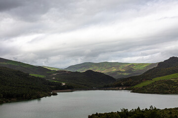 Hills and forest on the lake with dramatic sky and clouds