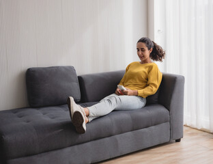 Portrait latin american woman one person smile happy sitting sofa and looking and hand holding use ...