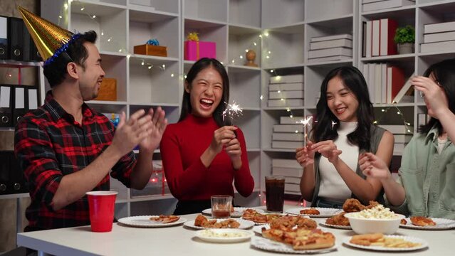 Group of happy Asian friends celebrate holiday using fireworks while holding party, birthday party, coworkers In the home office having fun snack concept holidays, lifestyle.