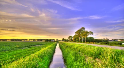 Foto op Plexiglas A small canal in a polder landscape in Holland at sunset. © Alex de Haas