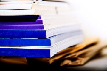 Stack of books on wooden table with white background, selective focus.