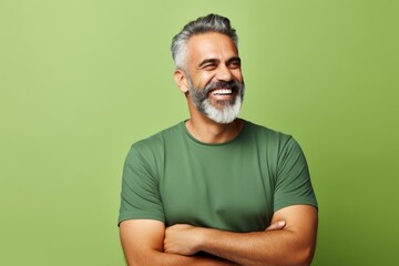 Portrait of a happy mature man with beard and mustache against green background