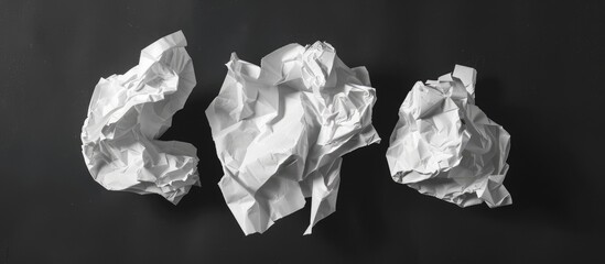 Three crumpled white pieces of paper against a black backdrop.