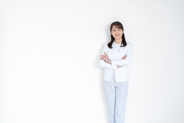 腕組をする白いスーツを着たミドルの日本人女性