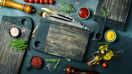 Black stone kitchen background with spices, herbs and kitchen utensils. Free space for text. Top view. Rustic style.