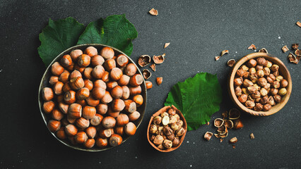 Hazelnuts, nut shells and nut kernels in a bowl. On a black stone background. Top view.