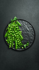 young green peas on a black stone plate. Creative advertising photo. On a black stone background. Top view. Green style.