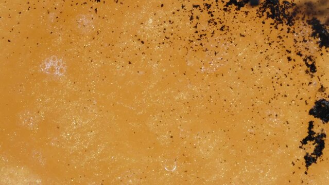 Chemical Reaction Macro, Golden Liquid Shrinks when Black Powder is Added.