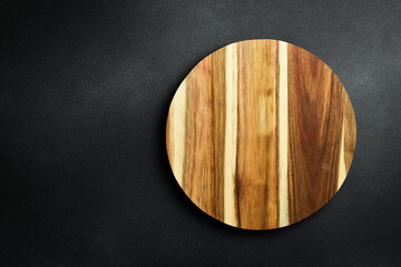 Kitchen wooden round board on a dark stone background. Top view. Free space for text.