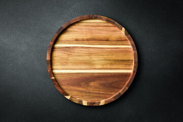 Kitchen wooden tray or board on a dark stone background. Top view. Free space for text.