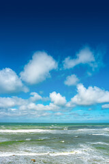 Cover page with oceanic seashore, at North Sea sandy beach, summer sunny day with big rolling waves, blue sky and copy space with gradient background