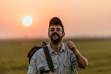 Cool guy with backpack taking a sunset stroll in the open fields