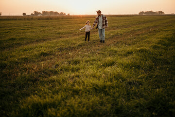 Fototapeta na wymiar Father and daughter bonding in a picturesque countryside setting as the sun sets behind them