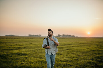 Young man with backpack exploring the countryside during sunset
