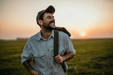 Trendy male wanderer strolling through open fields during twilight