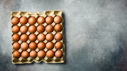 Top view, chicken eggs in a paper tray. On a gray concrete background.