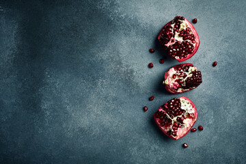 Top view closeup of fresh pomegranate pieces on concrete gray background.