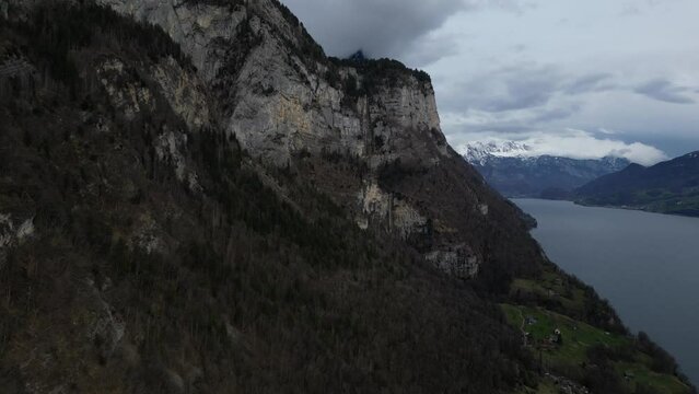 Drone shot of snow covered mountains by the cliff of hills at foreground in Walensee, Switzerland