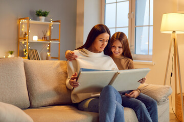 Mother and young daughter watching photo album, family in love, happy motherhood emotion. Friendly...