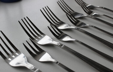 Silvery forks of different sizes in line on a clean white table

